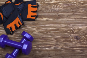 dumbbell and fitness gloves on wooden background