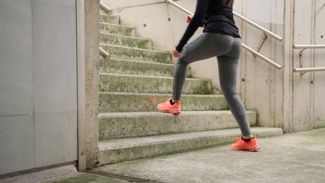 Step up exercise on urban stairs. Woman training hiit outside. Female athlete doing knee raises workout.
