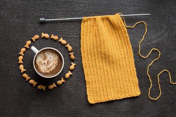 Knitting, cup of coffee and fish crackers in circle