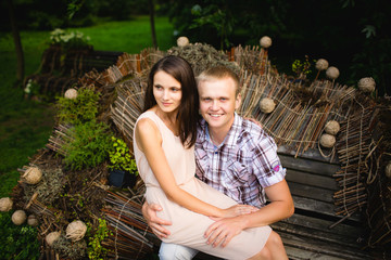 Young beautiful teen couple in love sitting together on the bench in the park.