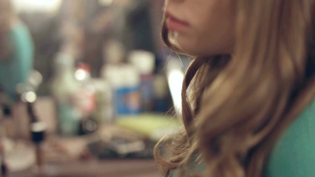 Hairdresser sprays hairspray on the hair of model 