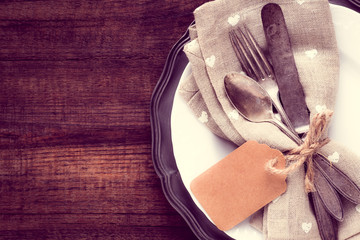 Vintage silverware on a plate against rustic wooden background. Concept of dinner or party