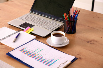 Laptop with stack of folders on table on white background