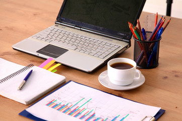 Laptop with stack of folders on table on white background