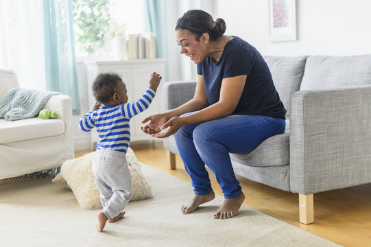 Mother playing with baby son in living room
