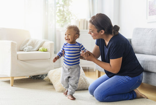 Mixed race mother playing with baby son in living room