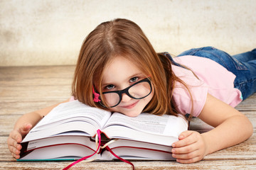 Young little girl wearing glasses and reading a book