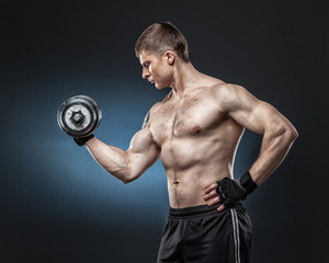 Fototapeta na wymiar Muscular yong man exercising with dumbbell