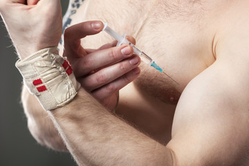 Closeup of a man injecting himself with steroids.