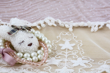 Fototapeta na wymiar White brooch like head of hare with light bracelets on pink lace as background