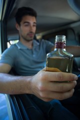 Slumped young man holding alcohol bottle 