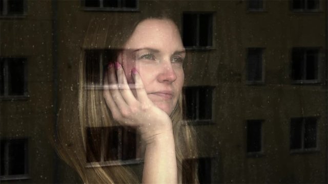 Sad young woman.
Young woman looking out of a window a rainy day, looking thoughtful and lonely.