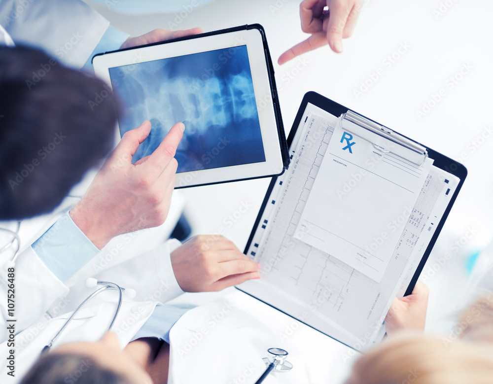 Poster group of doctors looking at x-ray on tablet pc