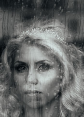 Beautiful romantic blonde bride posing near rainy window face cl