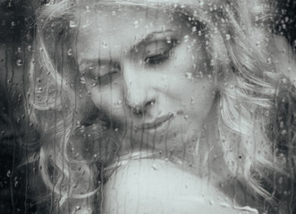 Beautiful romantic blonde bride posing near rainy window face cl