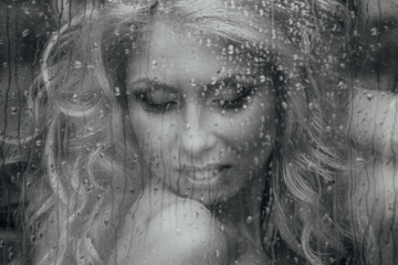 Beautiful romantic blonde bride posing near rainy window face cl