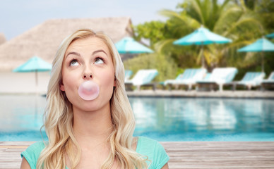 happy woman or teenage girl chewing gum on beach
