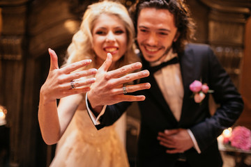 Newlywed couple, happy bride & groom posing with wedding rings