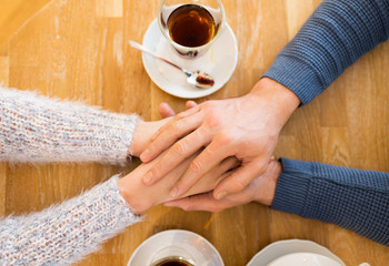 close up of couple holding hands at restaurant