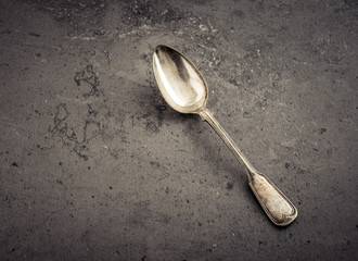 Silver spoon lying on stone table. Still life of vintage cutlery in kitchen. Concept of eating, cooking or restaurant.