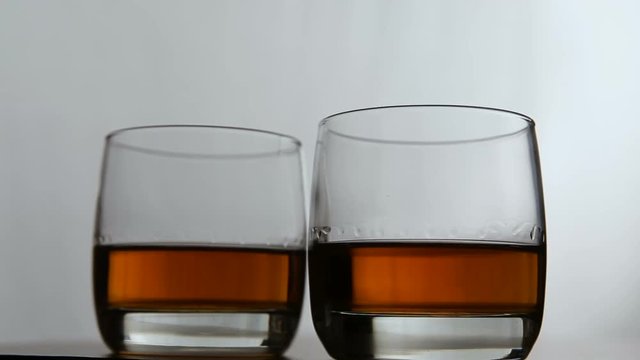 Two glasses of whiskey in the white background.Rotating glasses of whiskey.