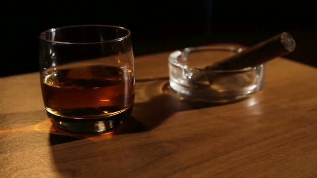 Glass of whiskey with smoking cigar.Glass of alcohol and smoking noble cigar on a black background.Rotating glasses of whiskey with smoking cigar.