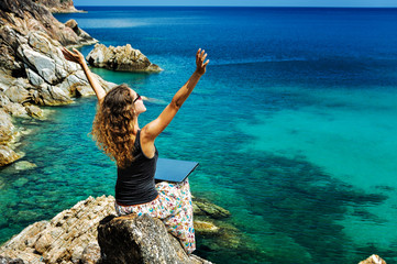 Woman freelancer feeling happy with laptop. Amazing seaview with blue lagoon with rocks. Happy lady...