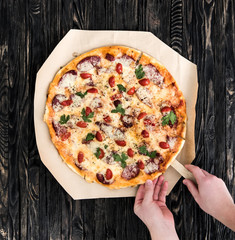 hands taking a portion of delicious pizza