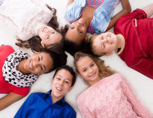 smiling children with different complexion lying head to head