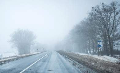 Fototapeta na wymiar foggy road with dirty snow on sides