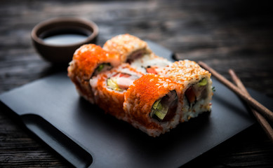 close up of sushi rolls on black tray