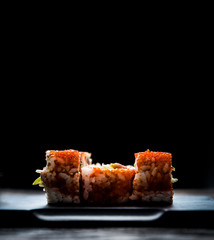 close up of sushi rolls on black tray