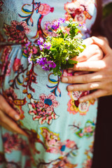 Pregnant holds a bunch of purple flowers