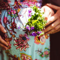 Bunch of flowers in the hands of pregnant in the sunny day