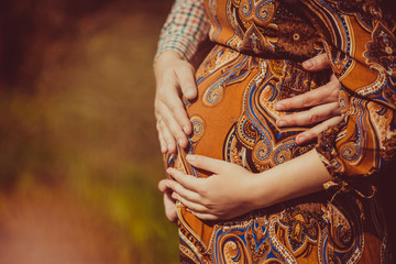 Man embraces the belly of his expectant woman