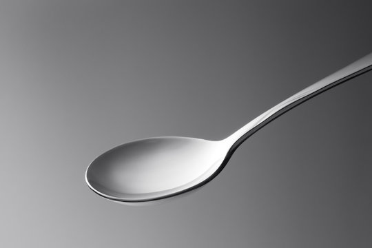 close up macro view of nice metal spoon on grey back