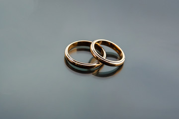 Celebratory accessories - two gold wedding rings for special day on glass grey background