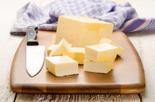 butter cubes and kitchen knife on a wooden board