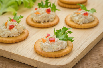 Crackers with tuna salad on wooden plate