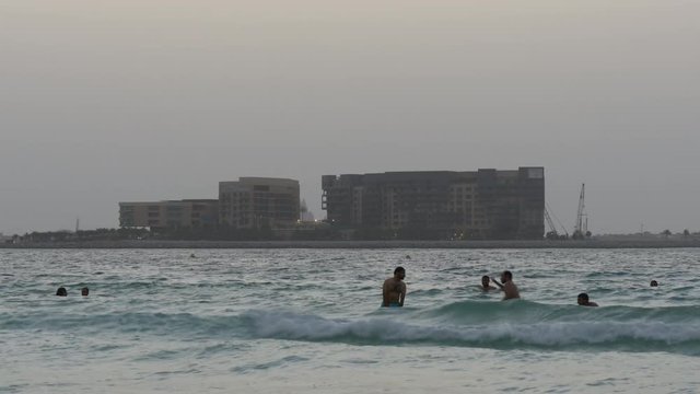 dubai evening swimers with a palm hotel construction view 4k uae
