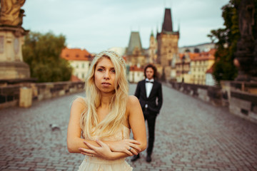 Beautiful blonde bride & handsome groom posing on Prague bridge,