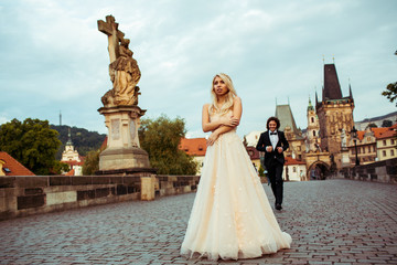 Obraz premium Happy newlywed groom running towards beautiful bride on bridge i