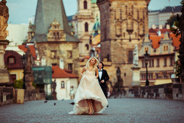 Obraz premium Happy newlywed groom running towards beautiful bride on bridge i