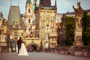 Fototapeta na wymiar Romantic newlywed couple on honeymoon, hugging on bridge in Prag