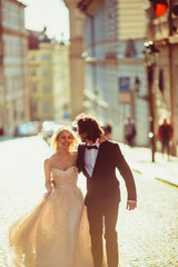 Naklejka premium Romantic newlyweds holding hands & walking in Prague street at s