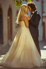 Fototapeta premium Fun couple, bride & groom holding hands in Prague street at suns