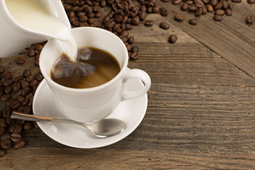 Pouring milk in a cup of coffee.