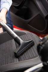 Man Hoovering Seat Of Car During Car Cleaning