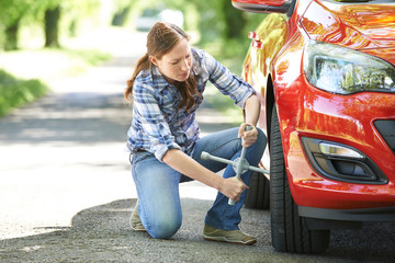 Frustrated Female Driver With Tyre Iron Trying To Change Wheel