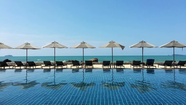Swimming pool with umbrella and chair, sea background.UHD 4K 3840x2160.
